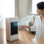 空気清浄機の内部構造と脱臭技術に興味深く触れる日本人の女性（家電ガイド運営者lead）。活性炭、イオン、そしてクエン酸などのメンテナンスアイテムが domestic なリビング/キッチンに配置されたアイキャッチ画像。