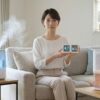 加湿器と除湿機の違いを解説する記事のアイキャッチ。加湿器と除湿機に挟まれ、湿度管理のメーターを持つ日本人女性。